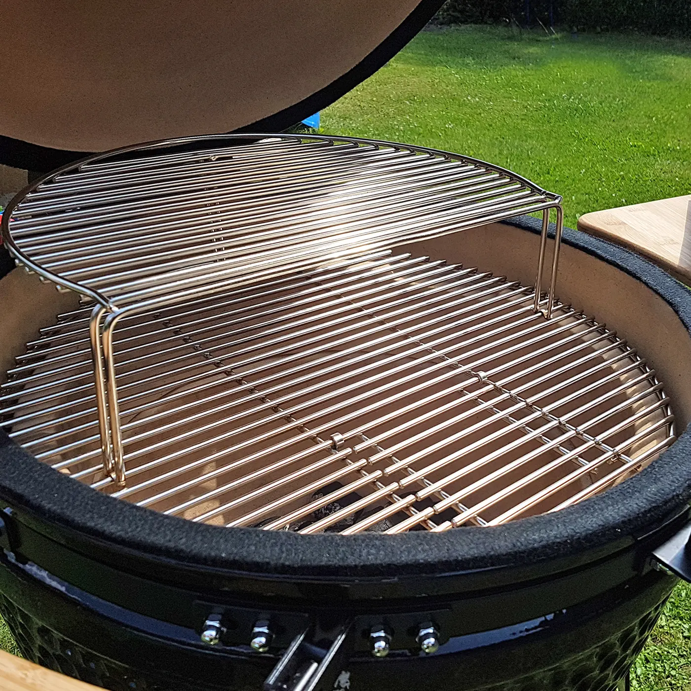 Geöffneter RedNeck Kamado mit zweistufigem Edelstahlrost im Garten